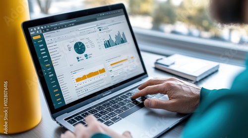 Person analyzing data on a laptop with charts and graphs on the screen.