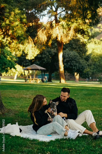 family hugging with a dog, walk in the park, outside french bulldog puppy with owner, young couple with a pet spending time outside the home, happy smiling people with a dog