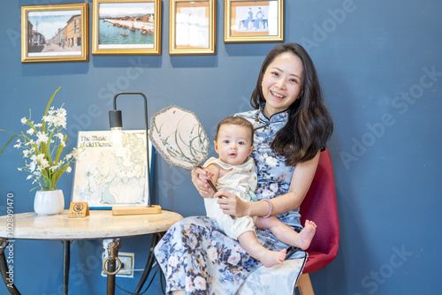 A Taiwanese woman in her 30s wearing traditional Chinese clothing sits while holding a 6-month-old baby and taking a commemorative photo on Dihua Street in Taipei City, Taiwan, in September. photo