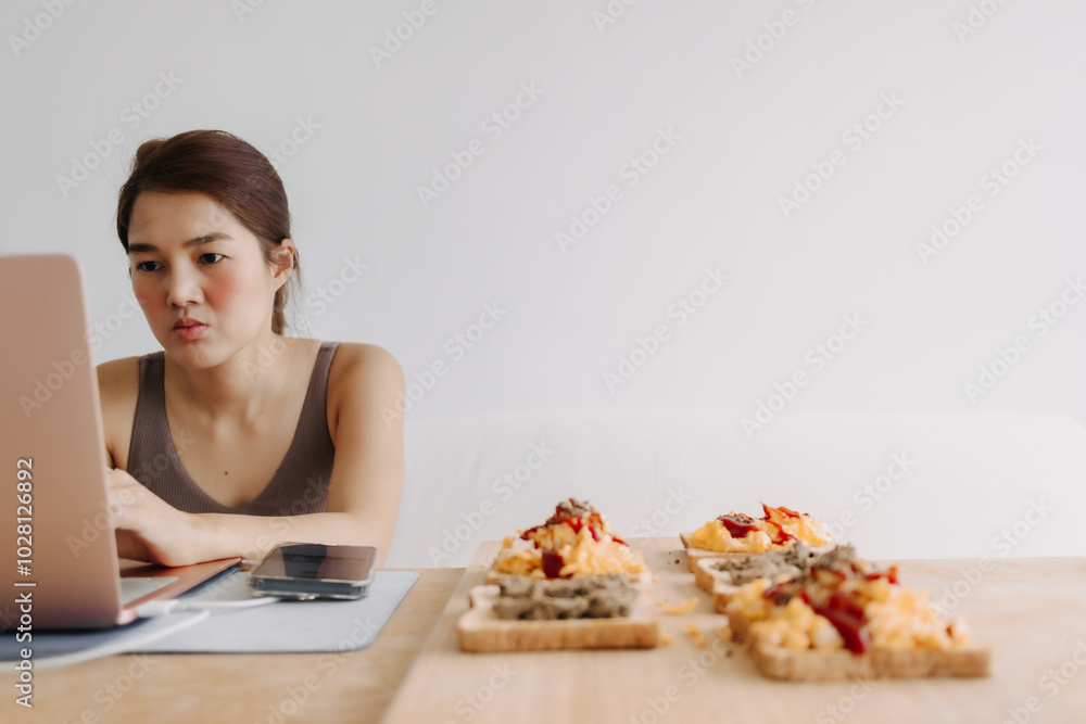 Asian woman is working at home with cozy clothes and breakfast meal. Asian woman is working at home with cozy clothes and breakfast meal.