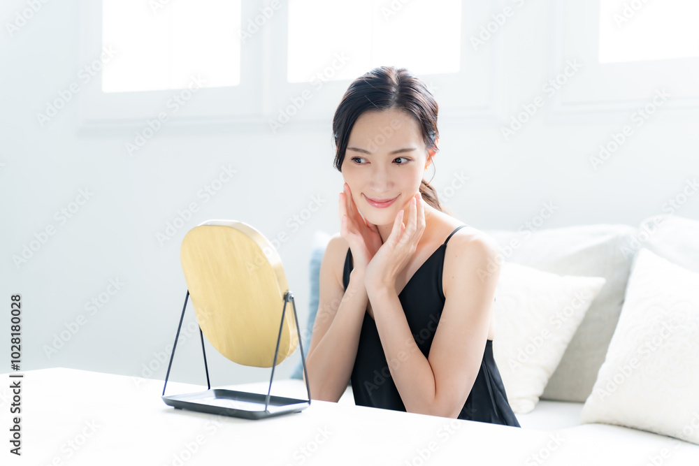 鏡を見て肌に触れるワンピースを着た女性