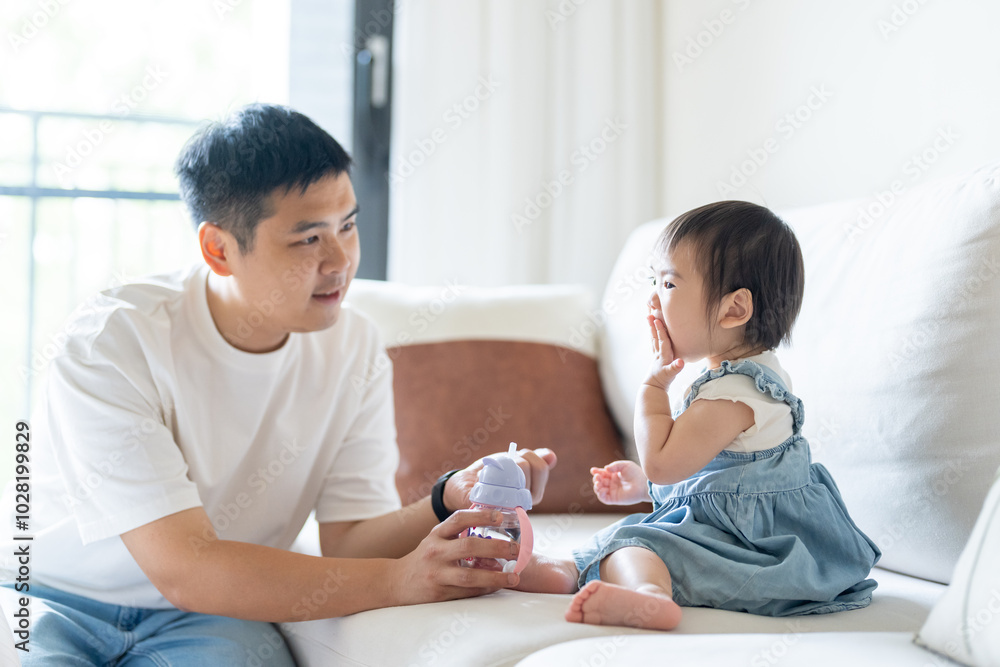 A 1 year old Taiwanese girl spending time playing happily with her parents, a man and woman in their 20s, in a room of a high rise apartment in Taichung City, Taiwan. A 1 year old Taiwanese girl spending time playing happily with her parents, a man and woman in their 20s, in a room of a high rise apartment in Taichung City, Taiwan.