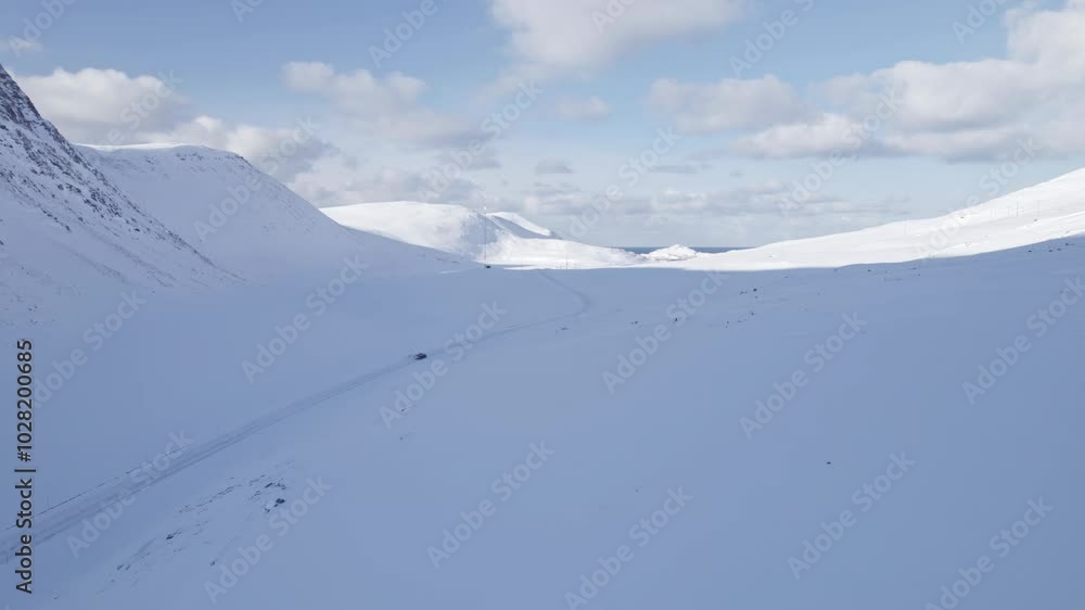 Winter holidays. Aerial view of a car driving through a snowy mountain valley. Winter holidays. Aerial view of a car driving through a snowy mountain valley.