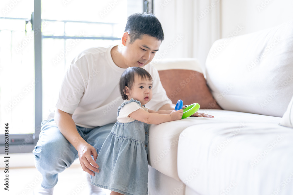 A 1 year old Taiwanese girl spending time playing happily with her parents, a man and woman in their 20s, in a room of a high rise apartment in Taichung City, Taiwan. A 1 year old Taiwanese girl spending time playing happily with her parents, a man and woman in their 20s, in a room of a high rise apartment in Taichung City, Taiwan.
