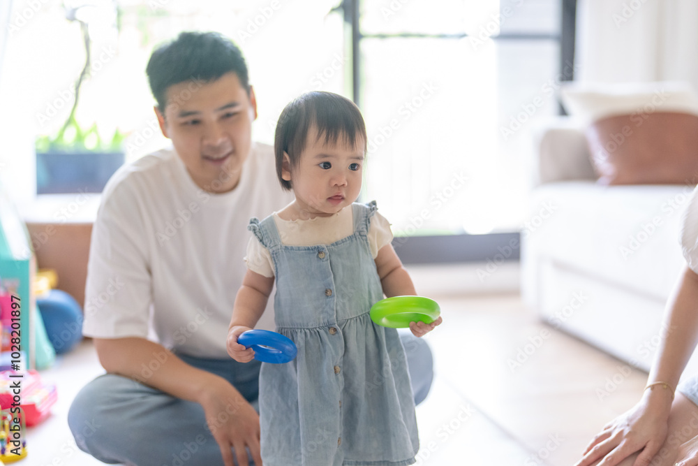 A 1 year old Taiwanese girl spending time playing happily with her parents, a man and woman in their 20s, in a room of a high rise apartment in Taichung City, Taiwan. A 1 year old Taiwanese girl spending time playing happily with her parents, a man and woman in their 20s, in a room of a high rise apartment in Taichung City, Taiwan.