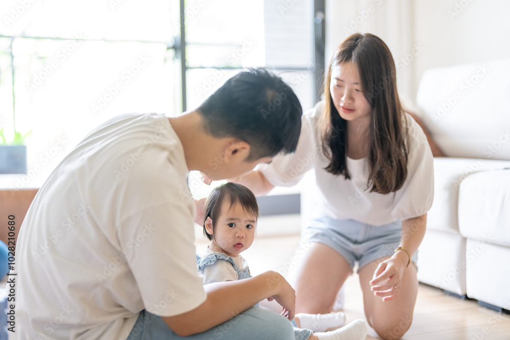 A 1 year old Taiwanese girl spending time playing happily with her parents, a man and woman in their 20s, in a room of a high rise apartment in Taichung City, Taiwan. A 1 year old Taiwanese girl spending time playing happily with her parents, a man and woman in their 20s, in a room of a high rise apartment in Taichung City, Taiwan.