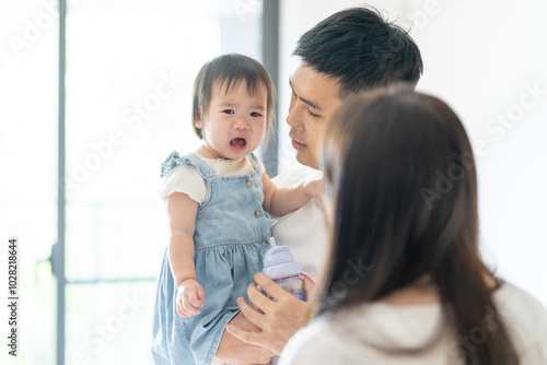 A 1 year old Taiwanese girl spending time playing happily with her parents, a man and woman in their 20s, in a room of a high rise apartment in Taichung City, Taiwan. photo