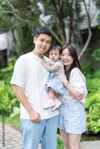 A 1 year old Taiwanese girl taking a commemorative photo with her parents, a man and woman in their 20s, on a hot sunny day in the streets of Taichung City, Taiwan, in September.