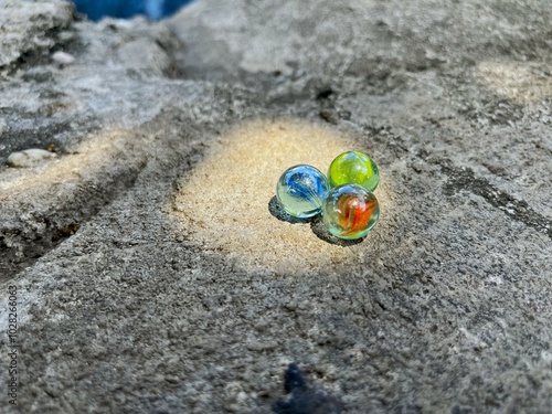 marbles or gundu are placed on a rough textured concrete surface photo