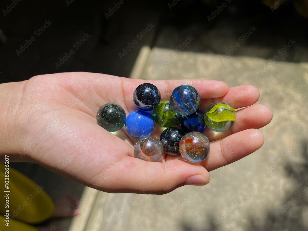 a pair of hands holding marbles. The marbles are colorful