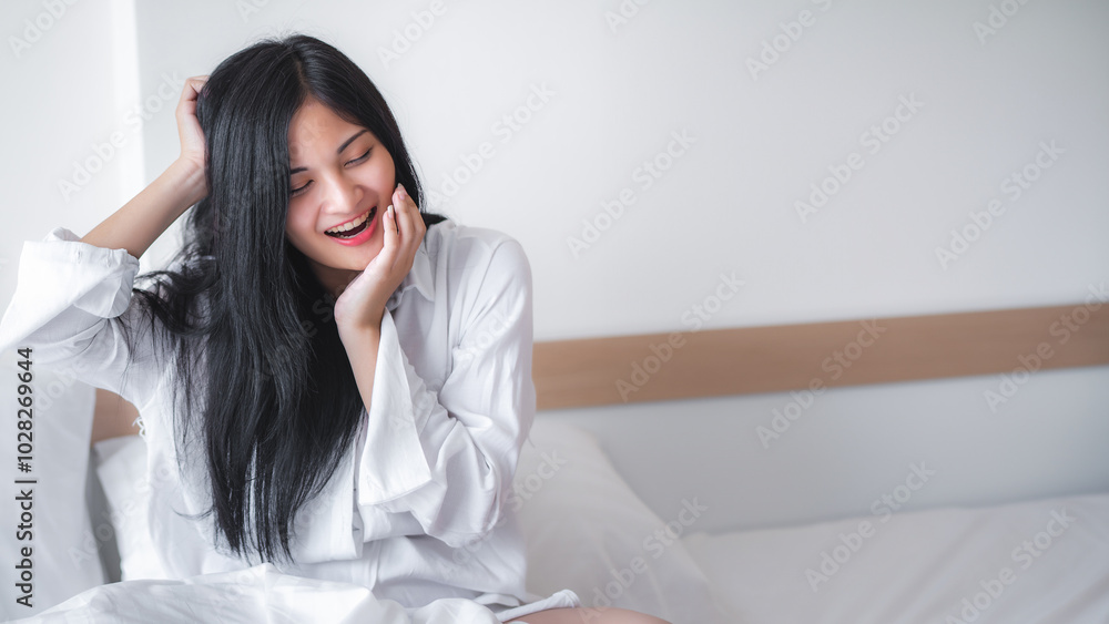 Beautiful young pretty Asian woman wake up and make happy smile with white shirt at the white bed in the morning. Beautiful young pretty Asian woman wake up and make happy smile with white shirt at the white bed in the morning.