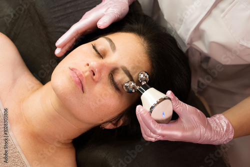 Beautician using microcurrent device on client’s forehead photo