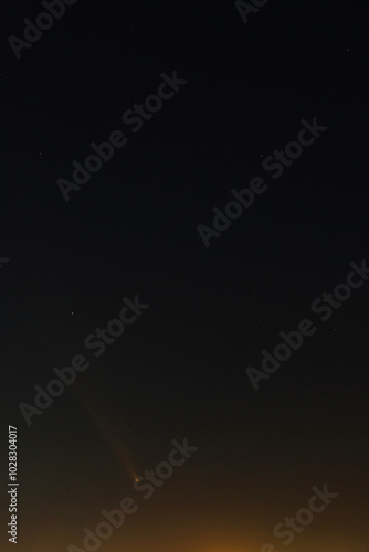 Comet Tsuchinshan Atlas 2023 A3 captured above the horizon, its glowing tail visible in the dark sky.