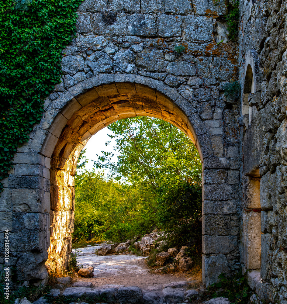 The wall of an ancient fortress with an arch illuminated by the sun. The wall of an ancient fortress with an arch illuminated by the sun.
