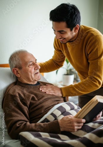 Caring young man supporting elderly father in bed with book