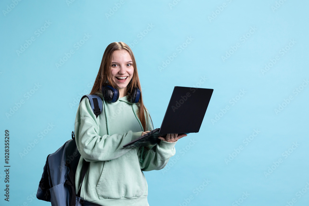 Obraz premium Portrait of cheerful woman carrying laptop needed to do school homework, isolated over studio background. Joyful pupil holding notebook, preparing for university assessment