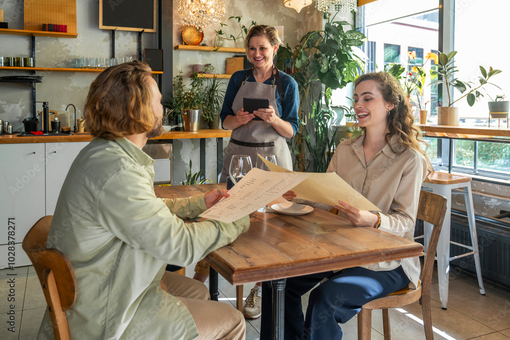 Waitress talking with happy customers sitting with menu cards at cafe Waitress talking with happy customers sitting with menu cards at cafe