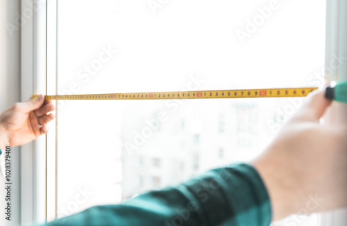 Man installs roller blinds. Handyman mesures window to fix it.