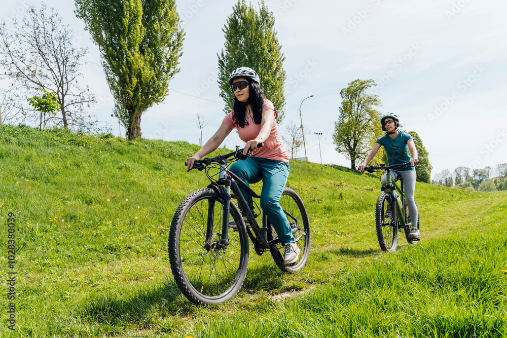 Friends riding bicycles on grass at meadow Friends riding bicycles on grass at meadow