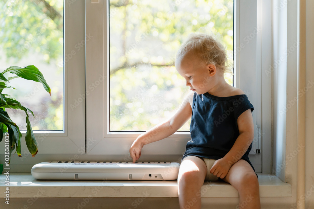 Boy sitting near window and playing with piano at home Boy sitting near window and playing with piano at home