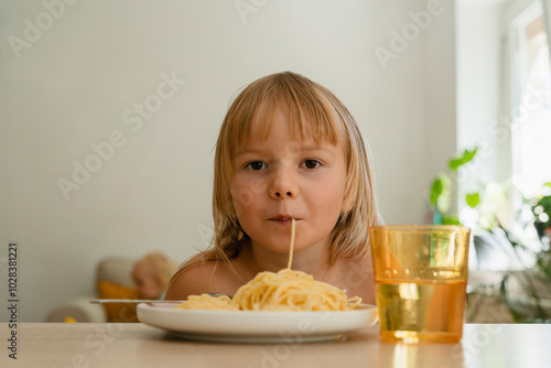 Blond girl with bangs eating spaghetti at home photo