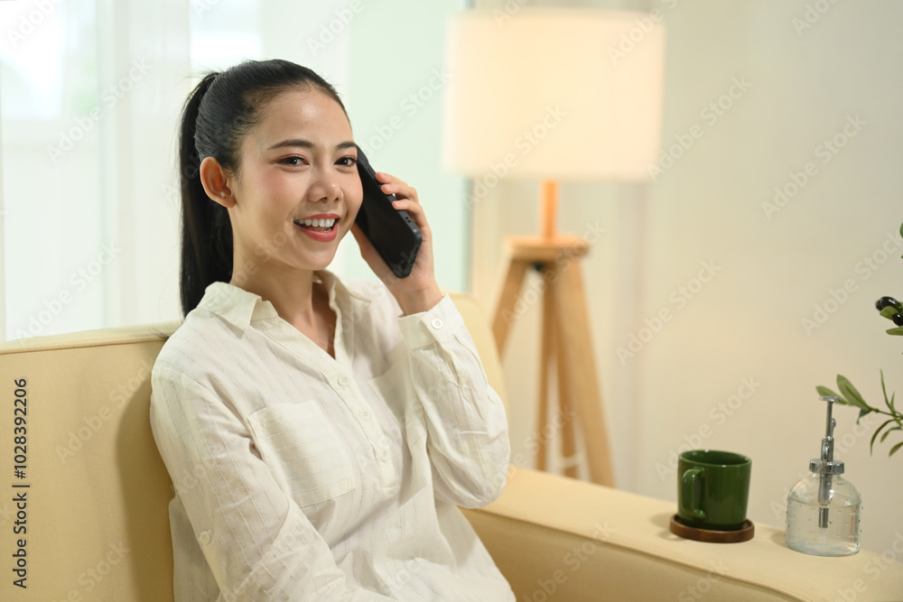 Attractive young woman sitting in modern office and talking on her mobile phone Attractive young woman sitting in modern office and talking on her mobile phone