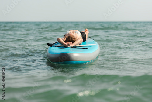 Woman lying on paddleboard and floating over black sea photo