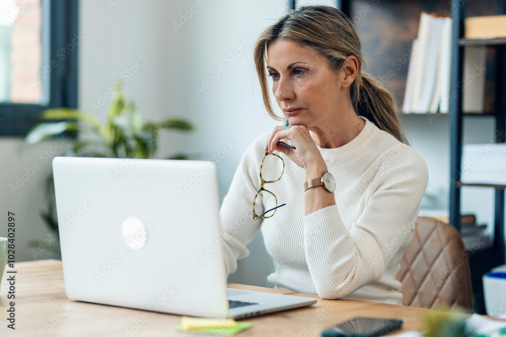 Blond businesswoman working on laptop at desk Blond businesswoman working on laptop at desk