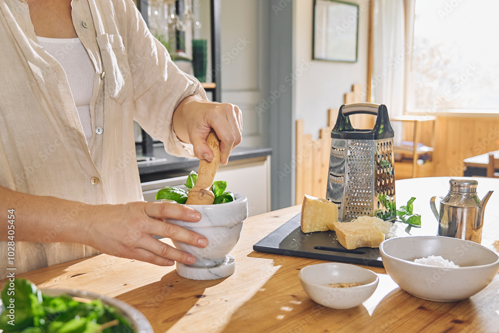 Woman making pesto genovese in mortar at home Woman making pesto genovese in mortar at home