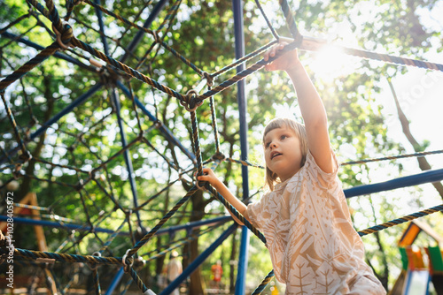 Girl climbing on rope jungle gym in playground photo