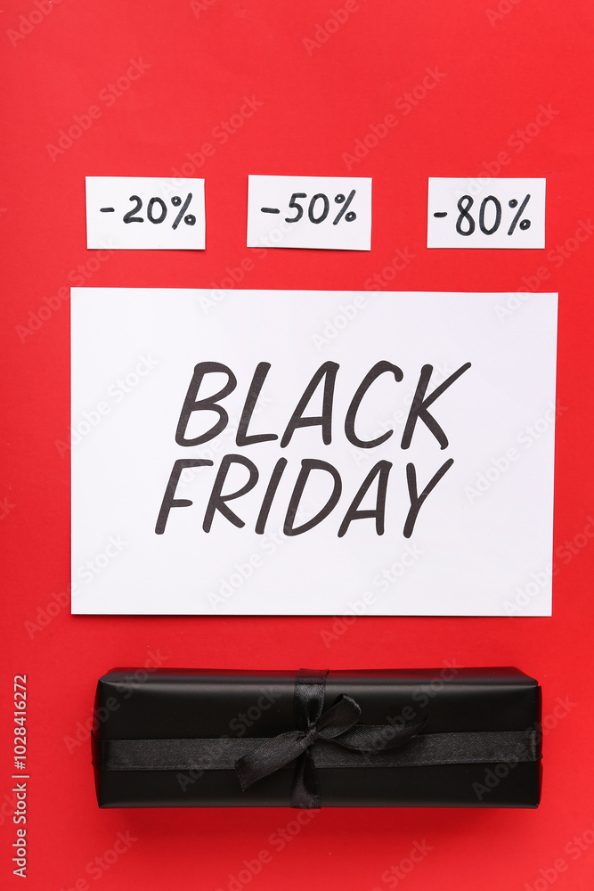 Naklejka premium Greeting card with text BLACK FRIDAY, gift box and discount tags on red background