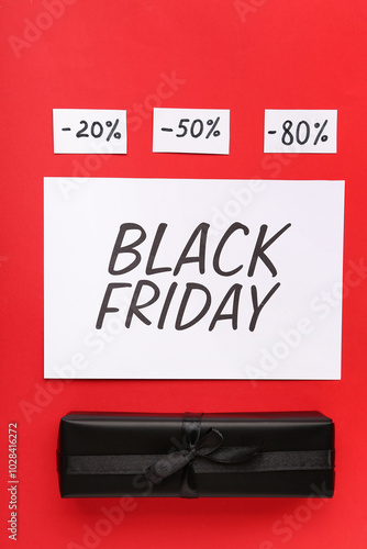 Greeting card with text BLACK FRIDAY, gift box and discount tags on red background