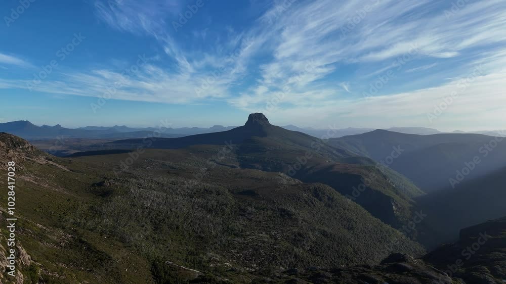 Aerial approaching shot of cradle mountain summit in national park during sunlight. Australian landscape with blue sky. Close up. Aerial approaching shot of cradle mountain summit in national park during sunlight. Australian landscape with blue sky. Close up.
