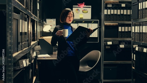 Portrait of investigator tracking financial transactions registered in the archives folders, looking for similarities and clues on criminology documents. Law agent working on forensics. Camera B. photo