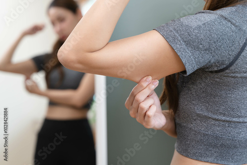 Foto Body care and weight loose concept, Close-up shot of woman looking at mirror grab her skin around under arm and worry about her figure
