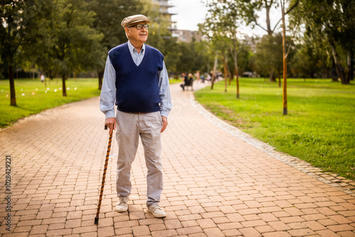 Portrait of happy senior man in park. He is relaxing and walking.