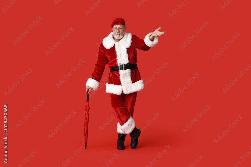 Santa Claus in glasses with umbrella on red background Santa Claus in glasses with umbrella on red background
