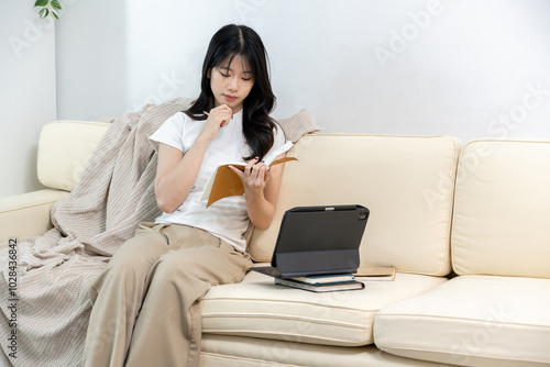 Young Asian woman taking notes during online meeting