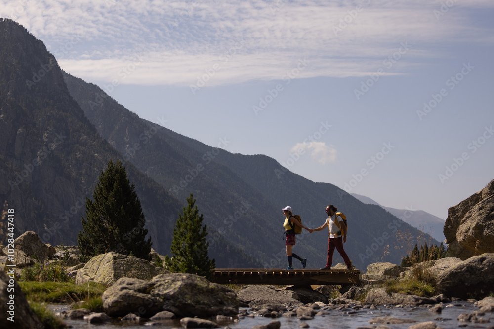 A couple is walking across a bridge over a river, with mountains in the background. Scene is peaceful and serene, as the couple enjoys the natural beauty of their surroundings A couple is walking across a bridge over a river, with mountains in the background. Scene is peaceful and serene, as the couple enjoys the natural beauty of their surroundings