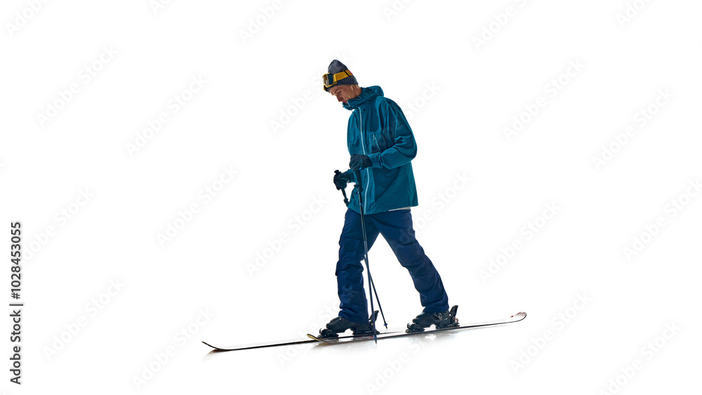 Young man dressed warm sport attire, goggles and skis, skiing in motion against white studio background. Ready for skiing on slope. Concept of extreme winter sports, vacation, speed, recreation. Ad Young man dressed warm sport attire, goggles and skis, skiing in motion against white studio background. Ready for skiing on slope. Concept of extreme winter sports, vacation, speed, recreation. Ad