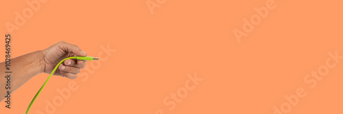 Black male hand holding a USB cable isolated on orange banner background