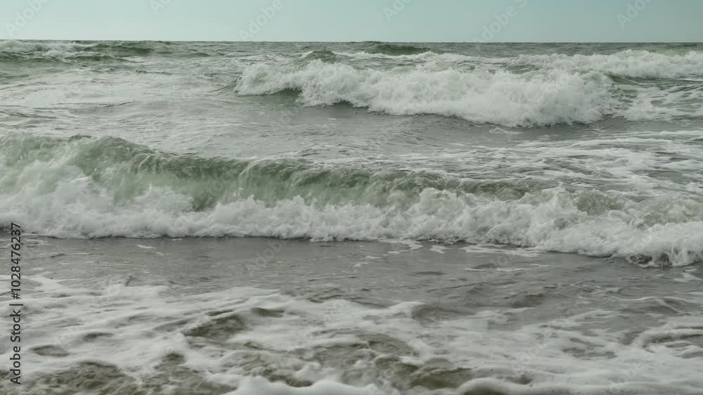 Waves crash on shore under overcast sky. Waves crash on shore under overcast sky.