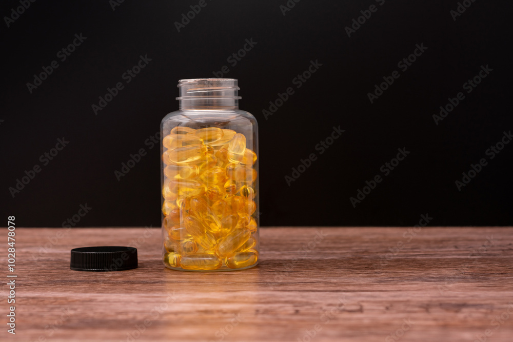 A bottle of yellow pills sits on a wooden table A bottle of yellow pills sits on a wooden table