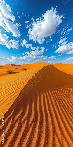 A stunning desert landscape with vibrant orange dunes and a blue sky dotted with fluffy clouds. photo