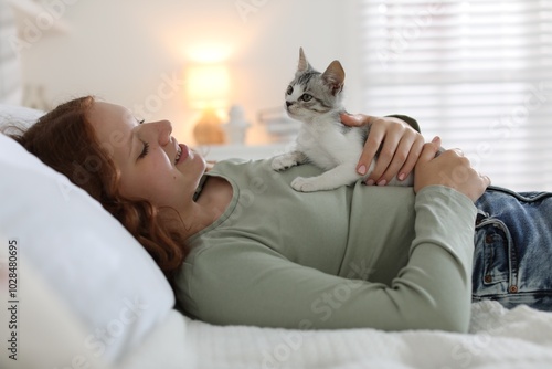 Beautiful teenage girl with cute cat on bed at home