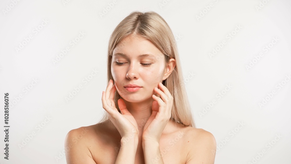 Young blonde woman posing at camera touching smooth face skin with fingers, isolated on white studio background. Beauty skin care concept Young blonde woman posing at camera touching smooth face skin with fingers, isolated on white studio background. Beauty skin care concept