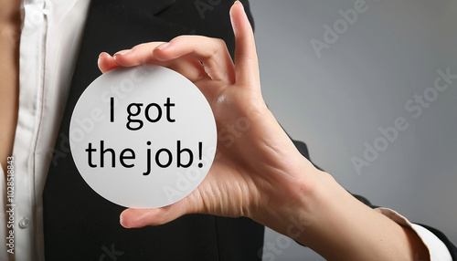 Hand holding a white card with I got the job