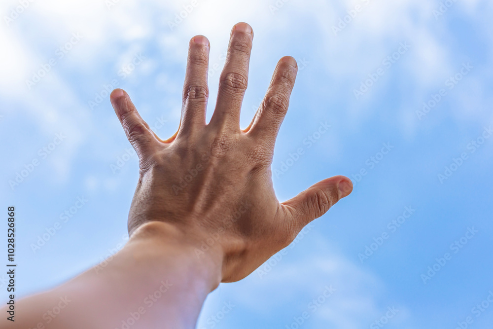 hands reaching upward against a backdrop of a blue sky with scattered clouds. hands reaching upward against a backdrop of a blue sky with scattered clouds.
