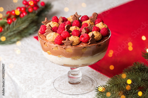 Christmas trifle or tiramisu with chocolate cream layer, ladyfingers, mascarpone cream, decorated with raspberries, amaretti cookies and festive shape mini cholates. photo