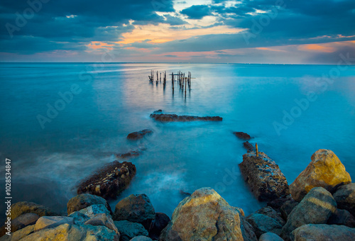 The twilight atmosphere before sunset at Ampenan Beach, Mataram, West Nusa Tenggara, Indonesia. A beautiful view of blue shades with sea water frozen using slow speed techniques. photo